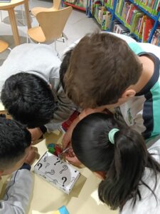 Estudiantes buscando libros y resolviendo pistas en la Biblioteca La Chata